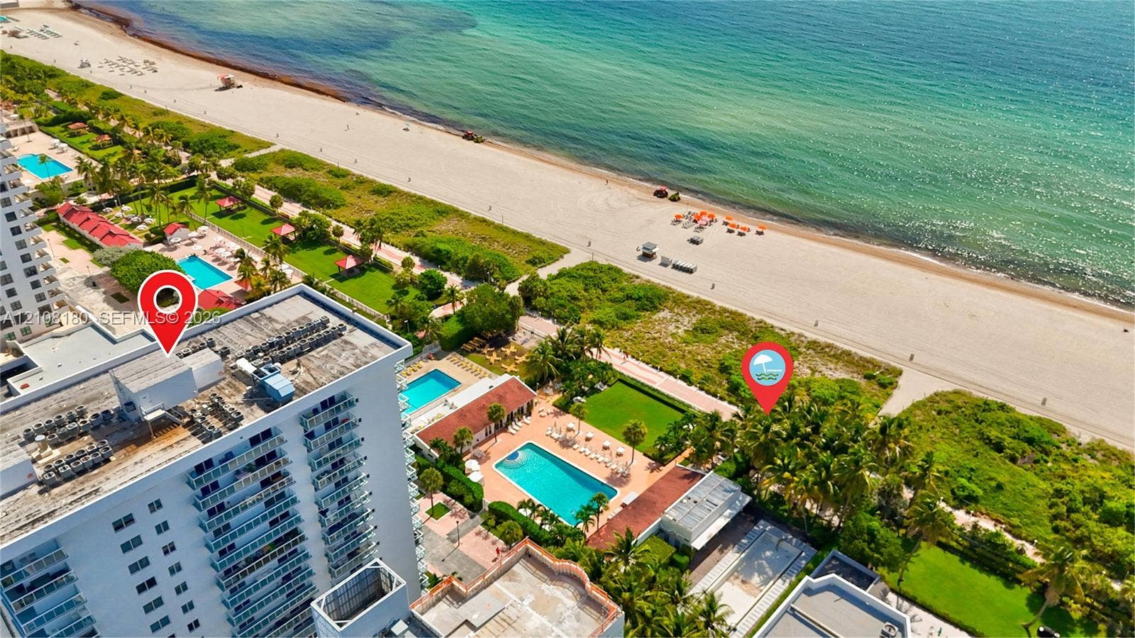 2457 Collins Avenue, #1501, Miami Beach, FL 33140 Aerial perspective of a high-rise building situated on a direct beachfront property, featuring an outdoor swimming pool, paved sundeck, and landscaped lawn areas
