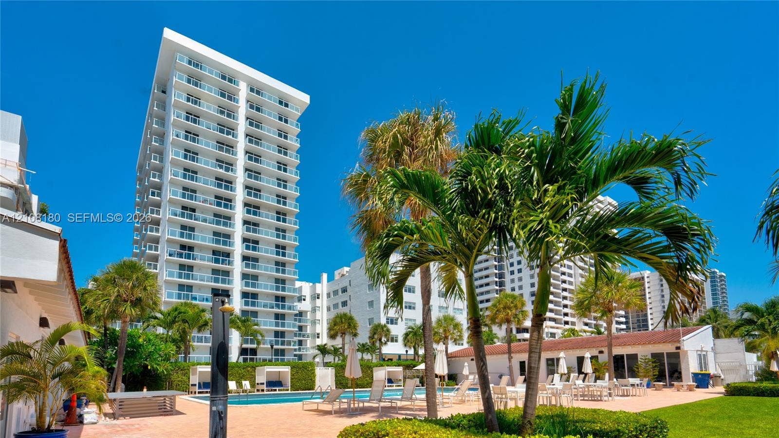 2457 Collins Avenue, #1501, Miami Beach, FL 33140 High-rise exterior featuring wraparound glass balconies, a swimming pool, paved pool deck, and landscaped palm trees