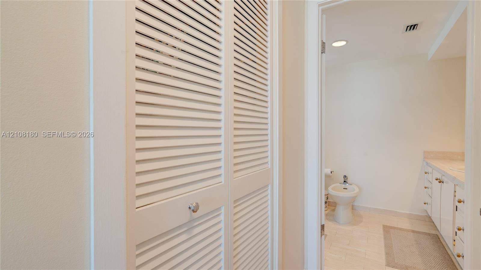 2457 Collins Avenue, #1501, Miami Beach, FL 33140 White louvered bifold closet doors featuring polished hardware, integrated white cabinetry with flat-panel drawers, and tile flooring