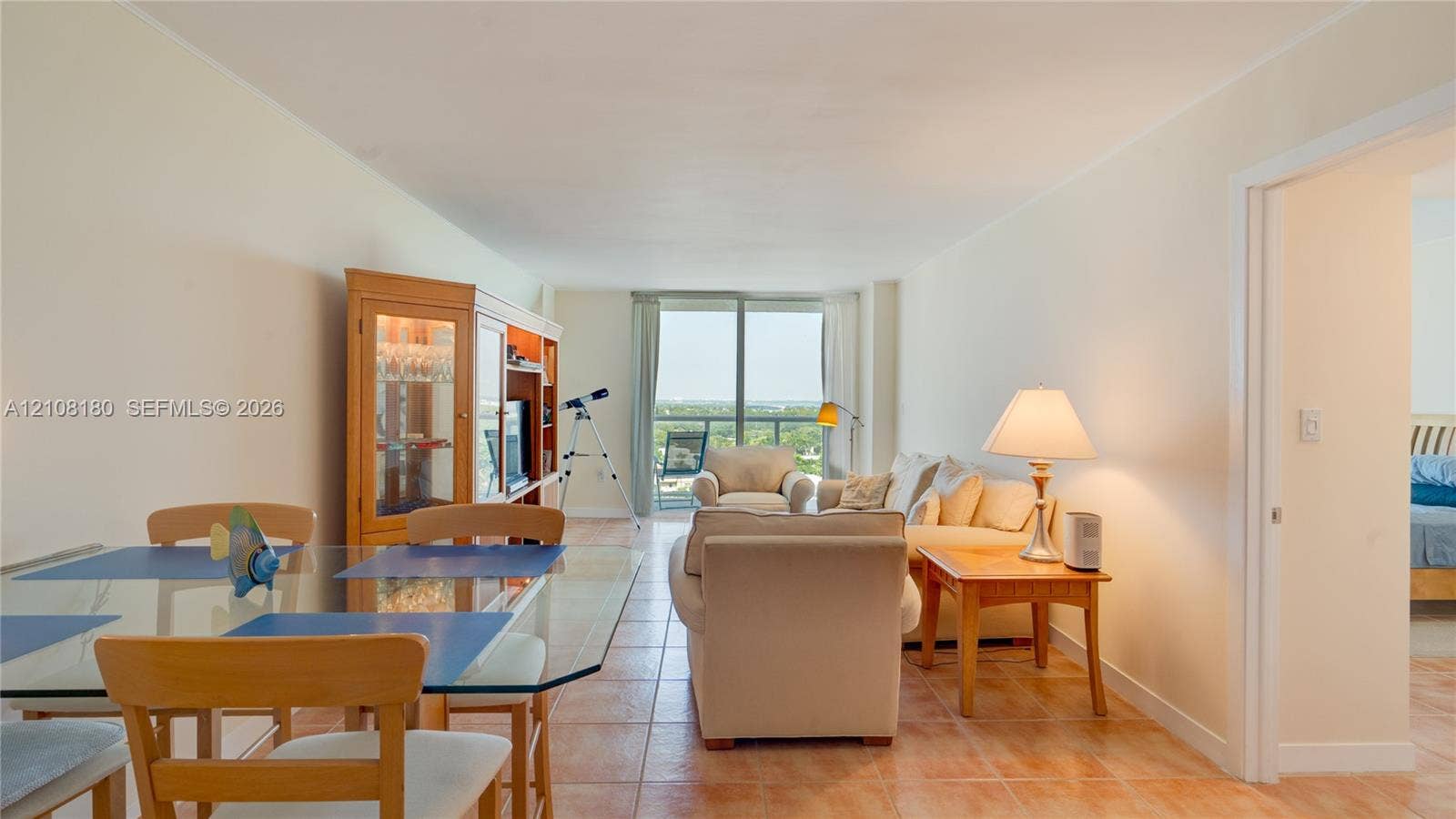2457 Collins Avenue, #1501, Miami Beach, FL 33140 Open-concept interior featuring neutral wall tones, large-format tile flooring, and floor-to-ceiling glass doors leading to a private balcony