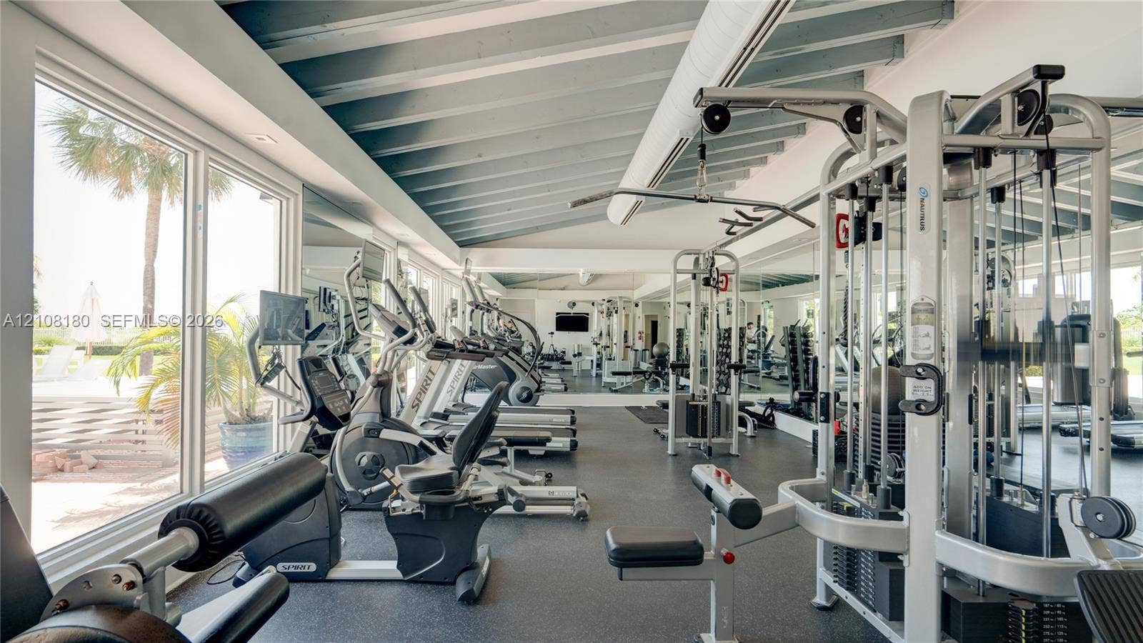 2457 Collins Avenue, #1501, Miami Beach, FL 33140 Exercise room featuring high sloped ceilings with exposed rafters, floor-to-ceiling windows, rubberized flooring, and full-length wall mirrors