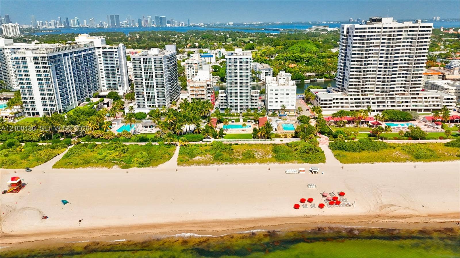 2457 Collins Avenue, #1501, Miami Beach, FL 33140 Aerial perspective of oceanfront property featuring sandy beach access, mature tropical landscaping, and outdoor swimming pools