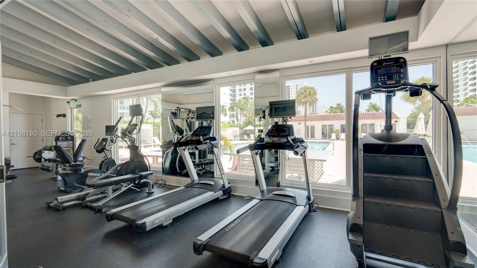 2457 Collins Avenue, #1501, Miami Beach, FL 33140 Fitness center featuring a vaulted ceiling with exposed beams, wall-to-wall mirrors, and floor-to-ceiling windows
