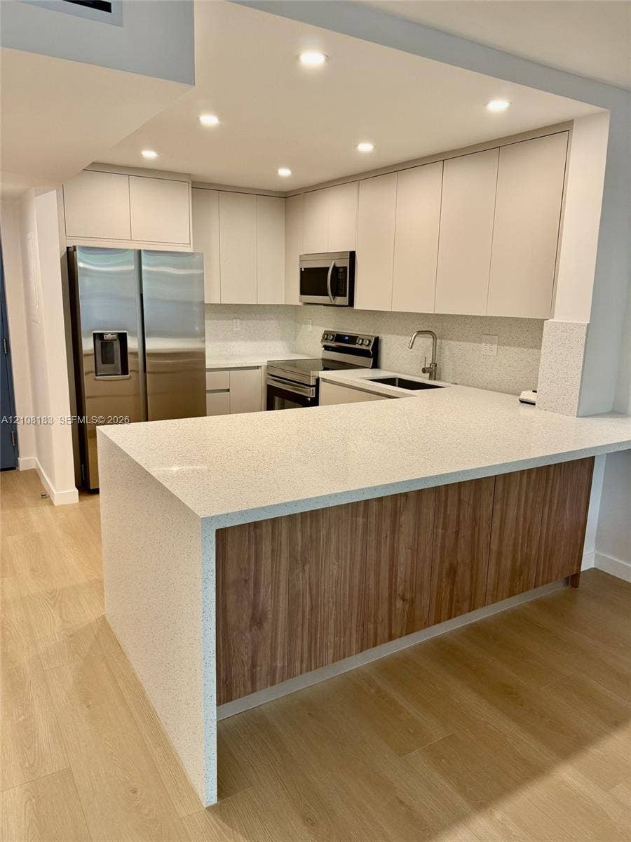 101 Ocean Lane Drive, #205, Key Biscayne, Key Biscayne, FL 33149 Kitchen featuring flat-panel cabinetry, light-toned stone-finish countertops, wood-finish island paneling, recessed lighting, and stainless steel appliances