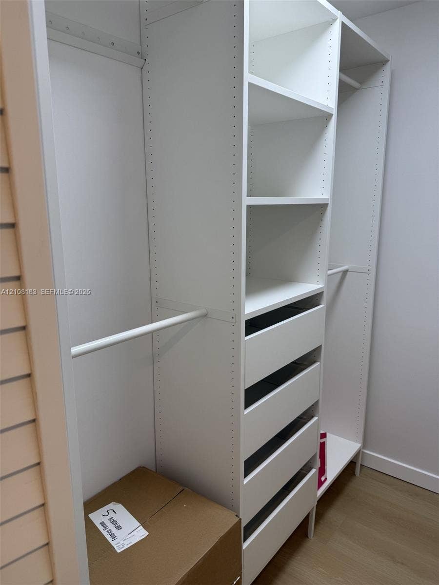 101 Ocean Lane Drive, #205, Key Biscayne, Key Biscayne, FL 33149 Built-in closet system featuring white modular cabinetry, adjustable shelving, integrated hanging rods, and a five-drawer unit