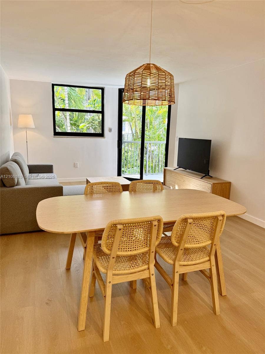 101 Ocean Lane Drive, #205, Key Biscayne, Key Biscayne, FL 33149 Living area featuring wood-finish flooring, a woven pendant light fixture, a black-framed window, and a sliding glass door providing external access