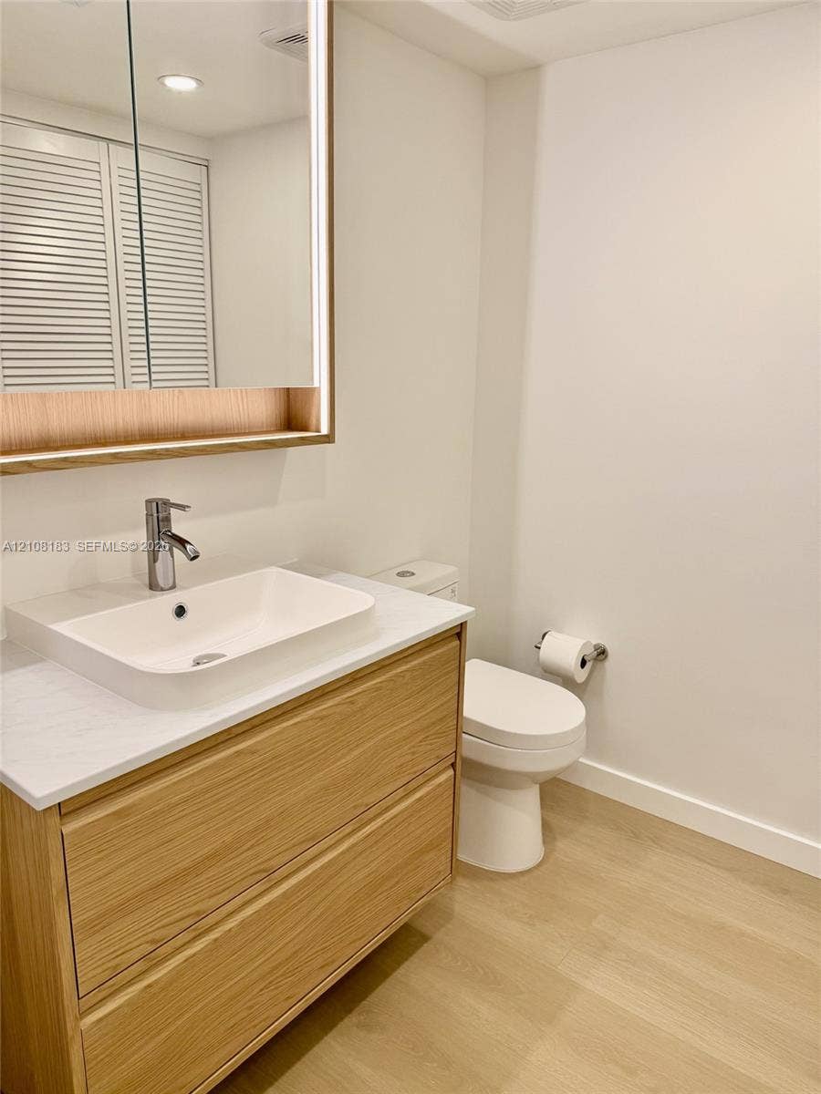 101 Ocean Lane Drive, #205, Key Biscayne, Key Biscayne, FL 33149 Floating wood-finish vanity with a rectangular sink, stone-composite countertop, integrated LED-lit medicine cabinet, and wood-finish flooring