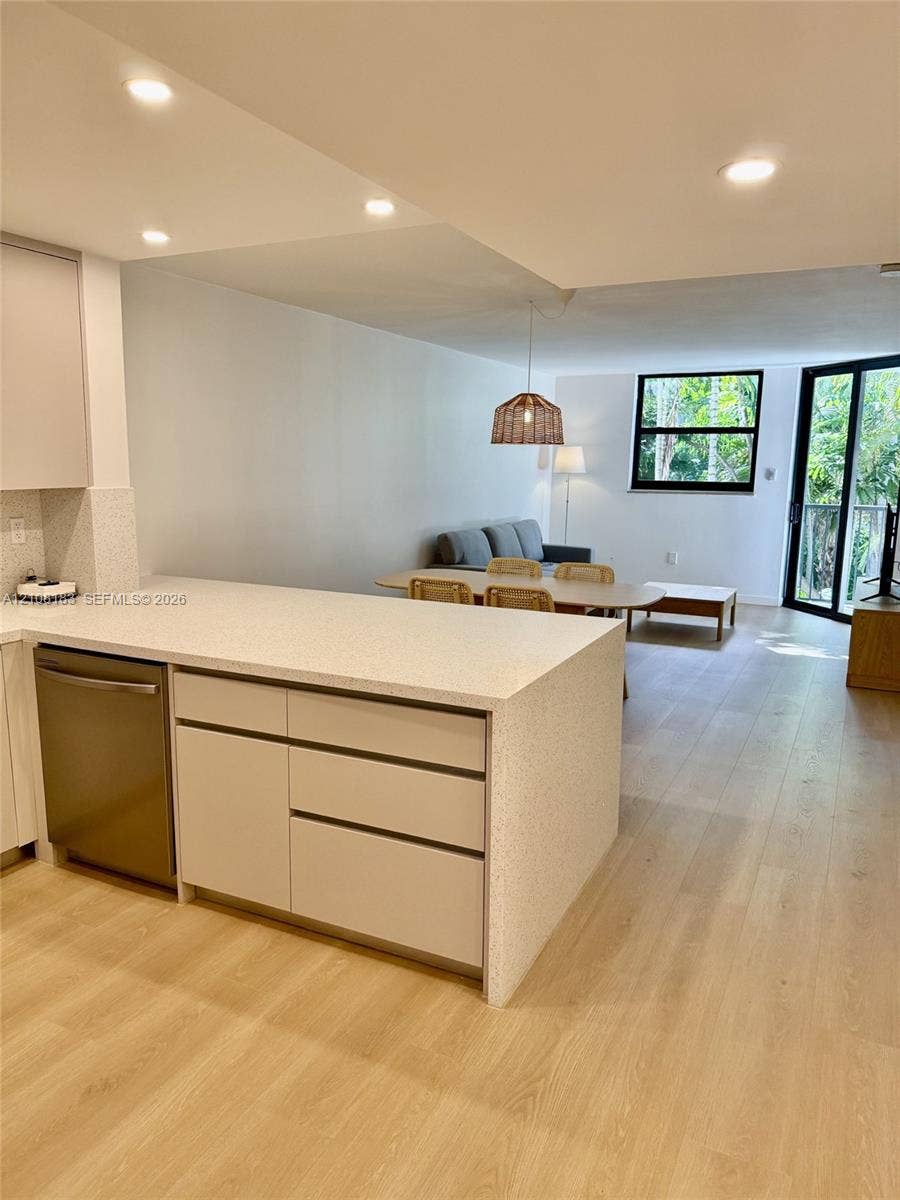 101 Ocean Lane Drive, #205, Key Biscayne, Key Biscayne, FL 33149 Kitchen featuring light-toned cabinetry, a stone-composite countertop island, stainless steel dishwasher, wood-finish flooring, and recessed ceiling lighting