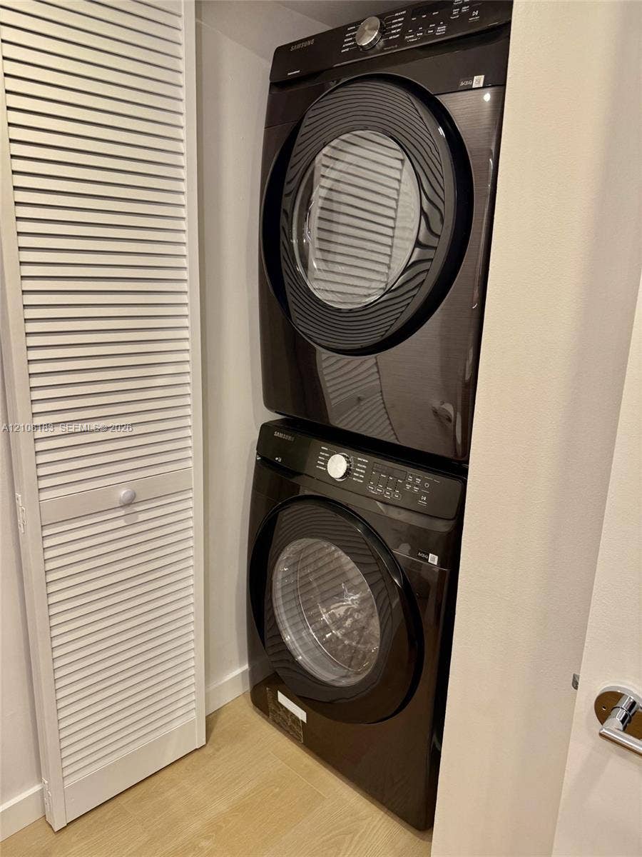 101 Ocean Lane Drive, #205, Key Biscayne, Key Biscayne, FL 33149 Stacked black high-efficiency laundry appliances set within a dedicated closet featuring louvered bi-fold doors and wood-finish flooring