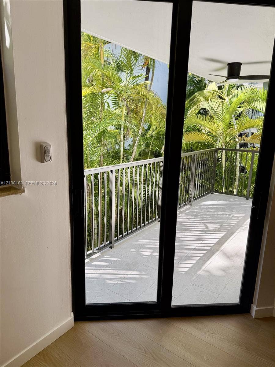 101 Ocean Lane Drive, #205, Key Biscayne, Key Biscayne, FL 33149 Covered balcony featuring black metal railings, large-format tile flooring, a ceiling fan, and mature palm trees