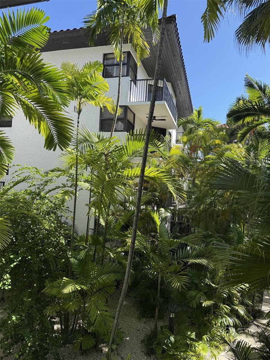 101 Ocean Lane Drive, #205, Key Biscayne, Key Biscayne, FL 33149 Multi-story exterior featuring white stucco siding, a tiled roof, metal balcony railings, and lush palm landscaping