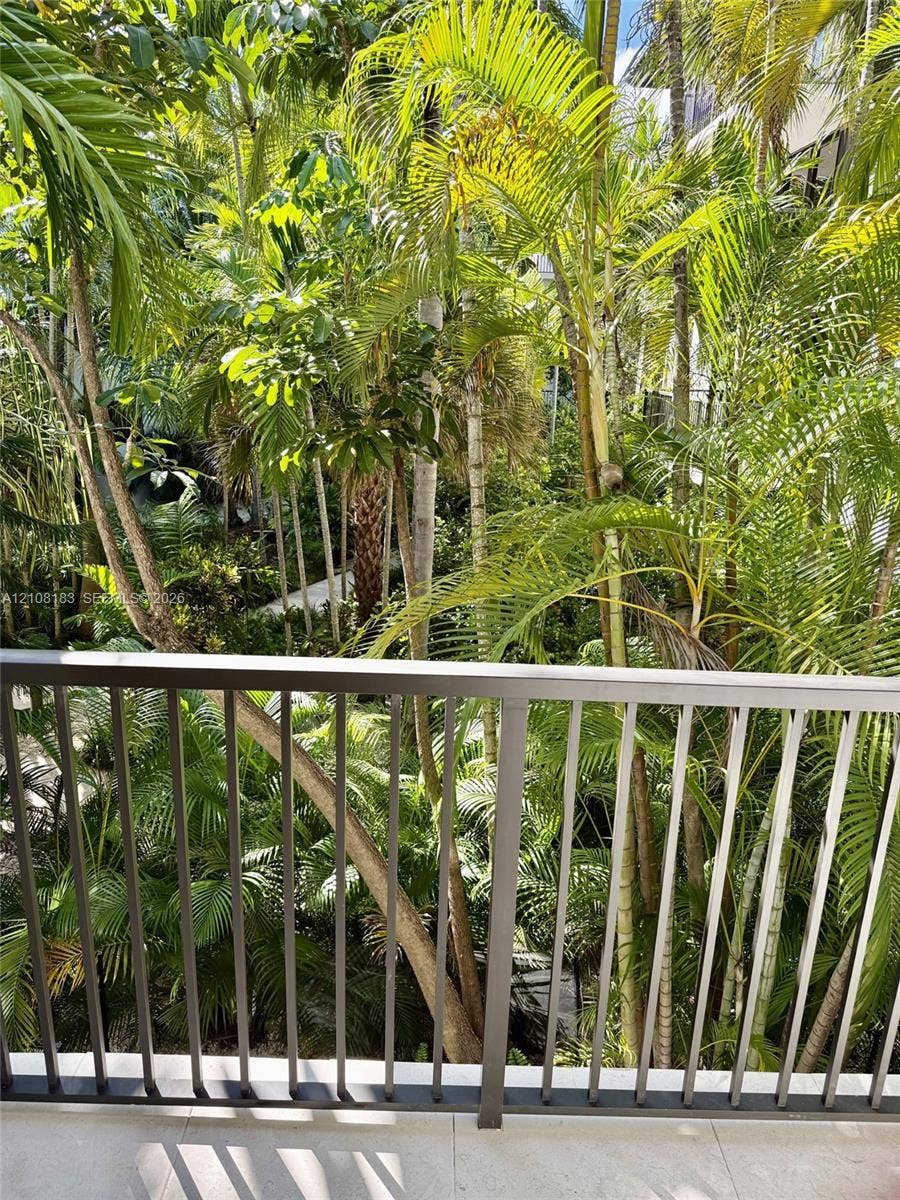 101 Ocean Lane Drive, #205, Key Biscayne, Key Biscayne, FL 33149 Balcony featuring a matte metal railing and stone-finish flooring overlooking dense, mature tropical landscaping