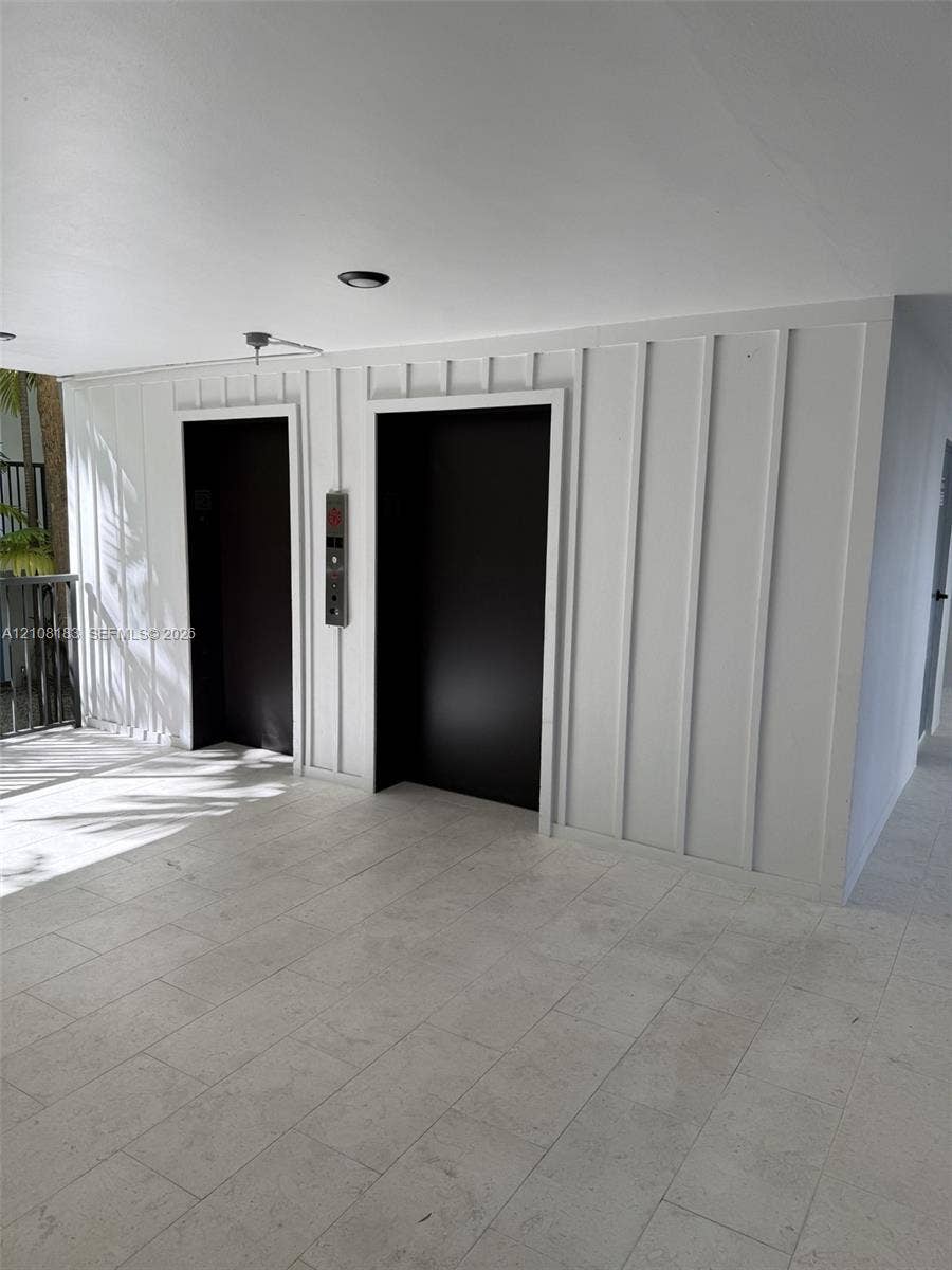 101 Ocean Lane Drive, #205, Key Biscayne, Key Biscayne, FL 33149 Dual elevator access featuring matte black entry portals, set against a board-and-batten accent wall with stone tile flooring and recessed ceiling lighting