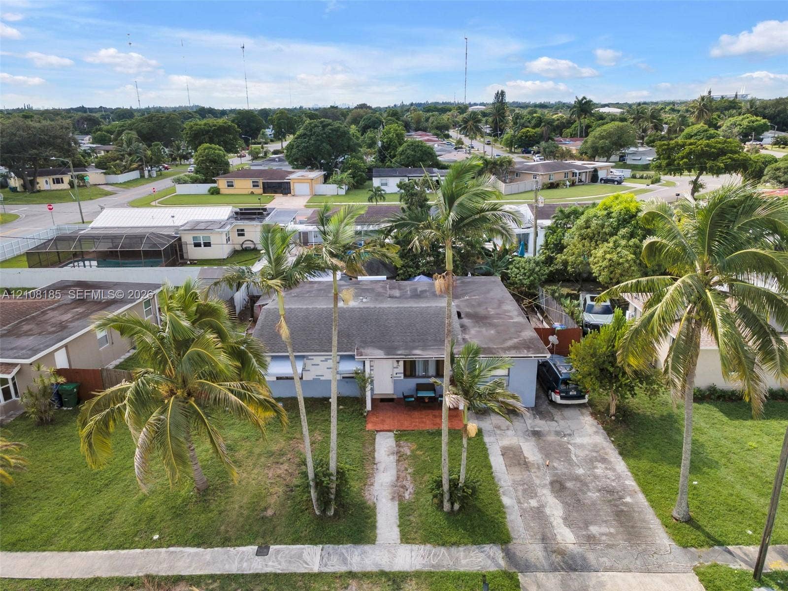 Single-story residence featuring a concrete driveway, a covered front entryway, and mature palm trees