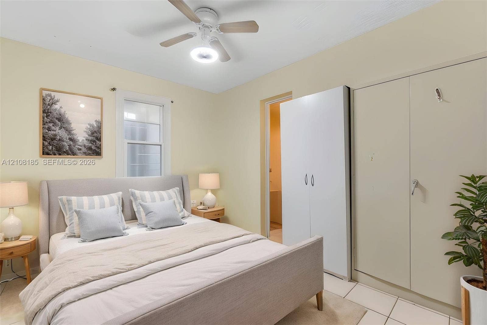 Room featuring white tile flooring, a ceiling fan with integrated lighting, and dual built-in closets
