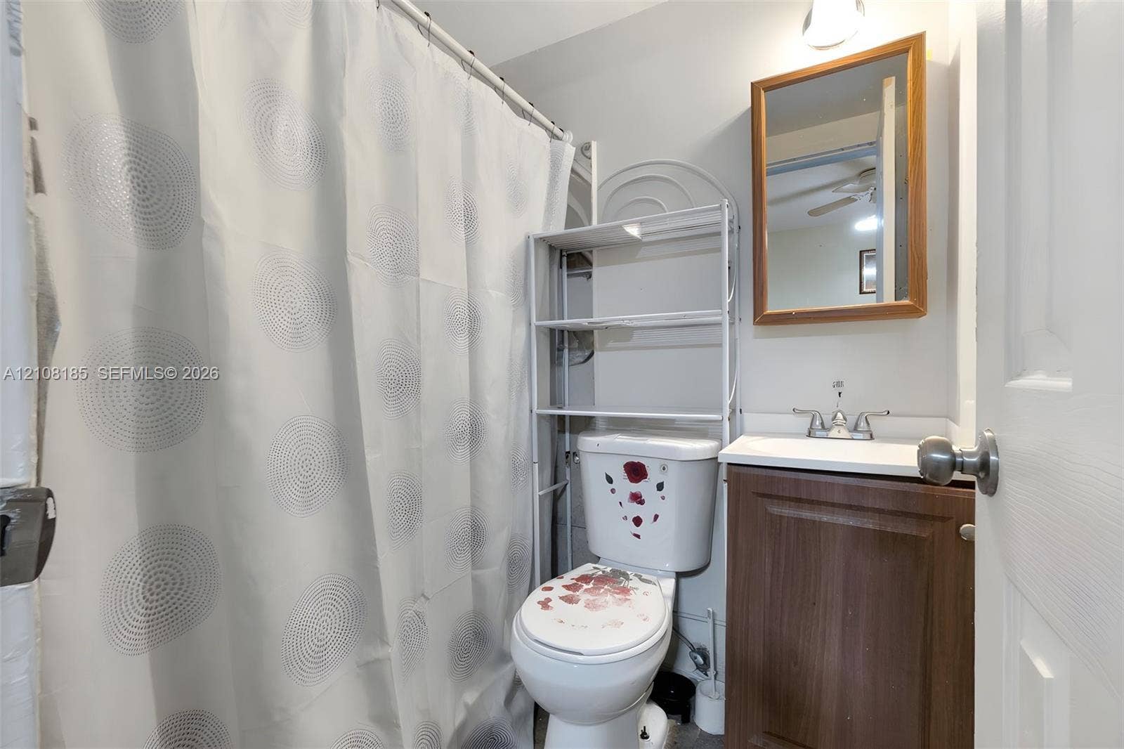 Bathroom featuring a wood-finish vanity cabinet, white sink basin, metallic dual-handle faucet, and wall-mounted wooden-framed mirror