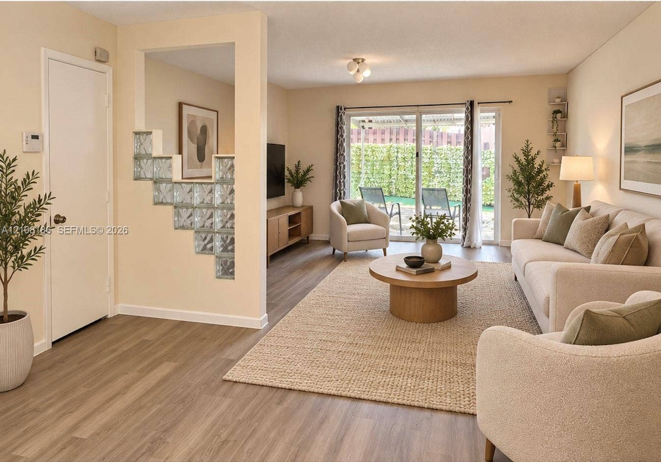 Living area featuring wood-finish flooring, a decorative glass block partition, and sliding glass doors providing outdoor access
