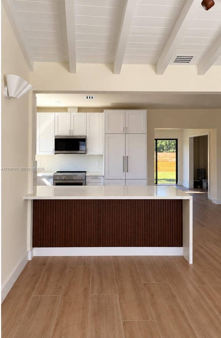 1929 SW 21st Street, #0, Miami, Miami, FL 33145 Kitchen featuring white cabinetry, wood-finish flooring, a quartz countertop, and a paneled breakfast bar with exposed ceiling beams