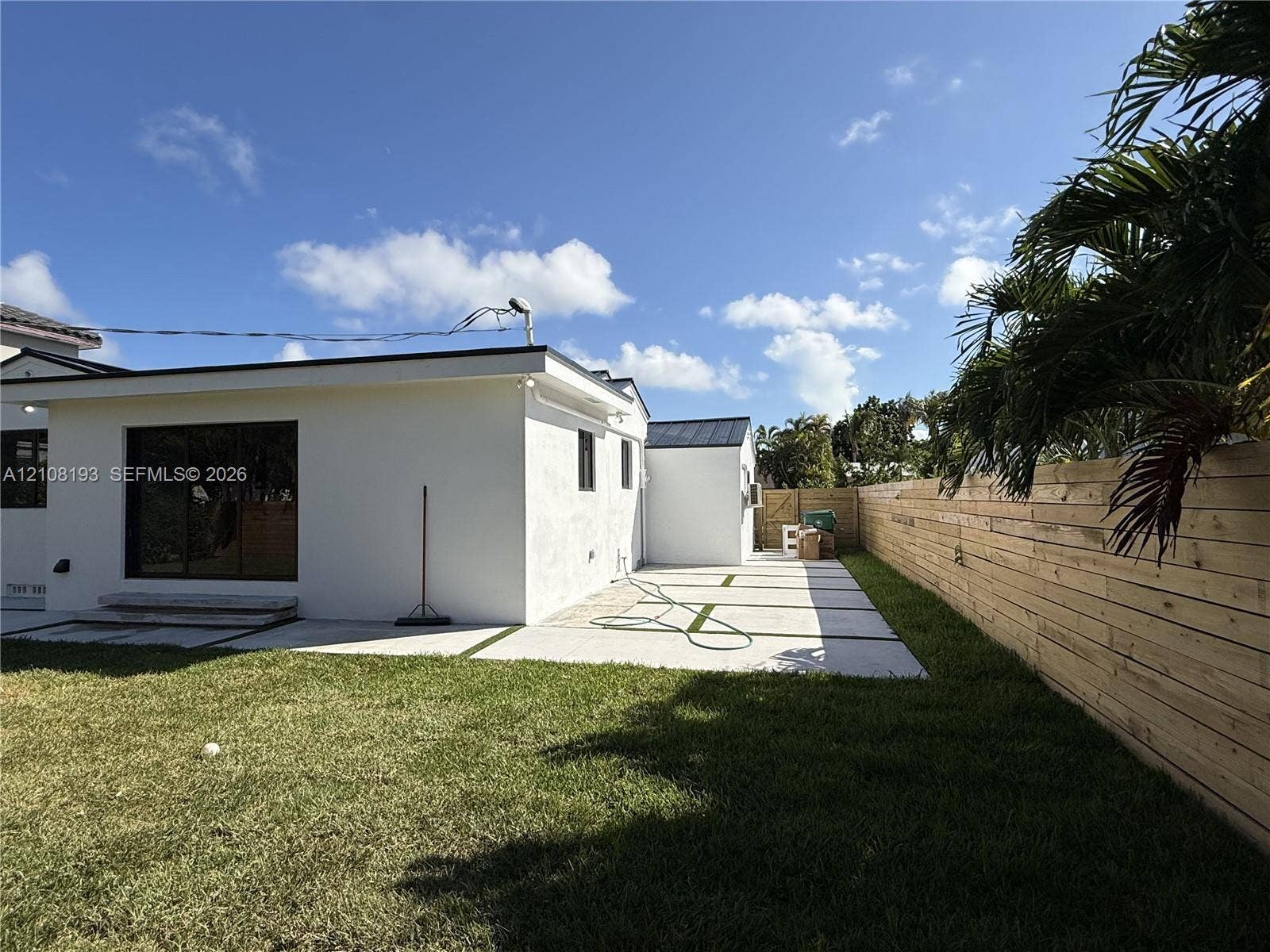 1929 SW 21st Street, #0, Miami, Miami, FL 33145 Backyard featuring a paved stone patio with grass inlays, horizontal wood privacy fencing, and sliding glass doors