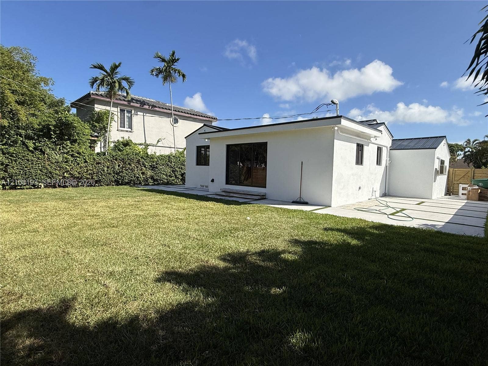 1929 SW 21st Street, #0, Miami, Miami, FL 33145 Backyard featuring a grass lawn, paved patio with inlay grass strips, sliding glass doors, and a perimeter hedge
