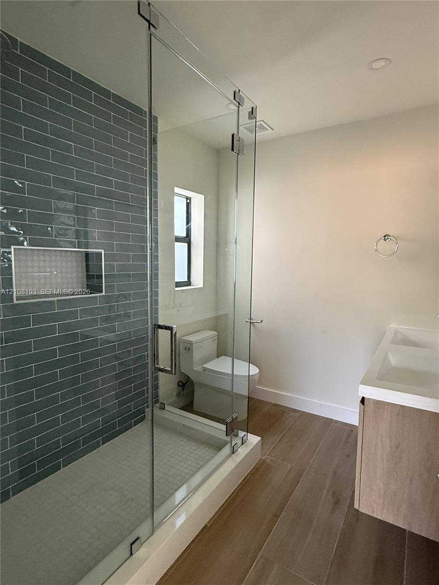 1929 SW 21st Street, #0, Miami, Miami, FL 33145 Walk-in shower featuring a glass enclosure, gray subway tile wall, and built-in recessed niche, complemented by wood-finish flooring and a floating dual-sink vanity