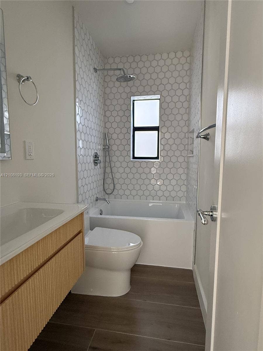 1929 SW 21st Street, #0, Miami, Miami, FL 33145 Bathroom featuring a wall-mounted floating vanity with textured wood-finish cabinet, tub-shower combination with floor-to-ceiling hexagonal tile surround, rainfall showerhead, and neutral wood-finish flooring