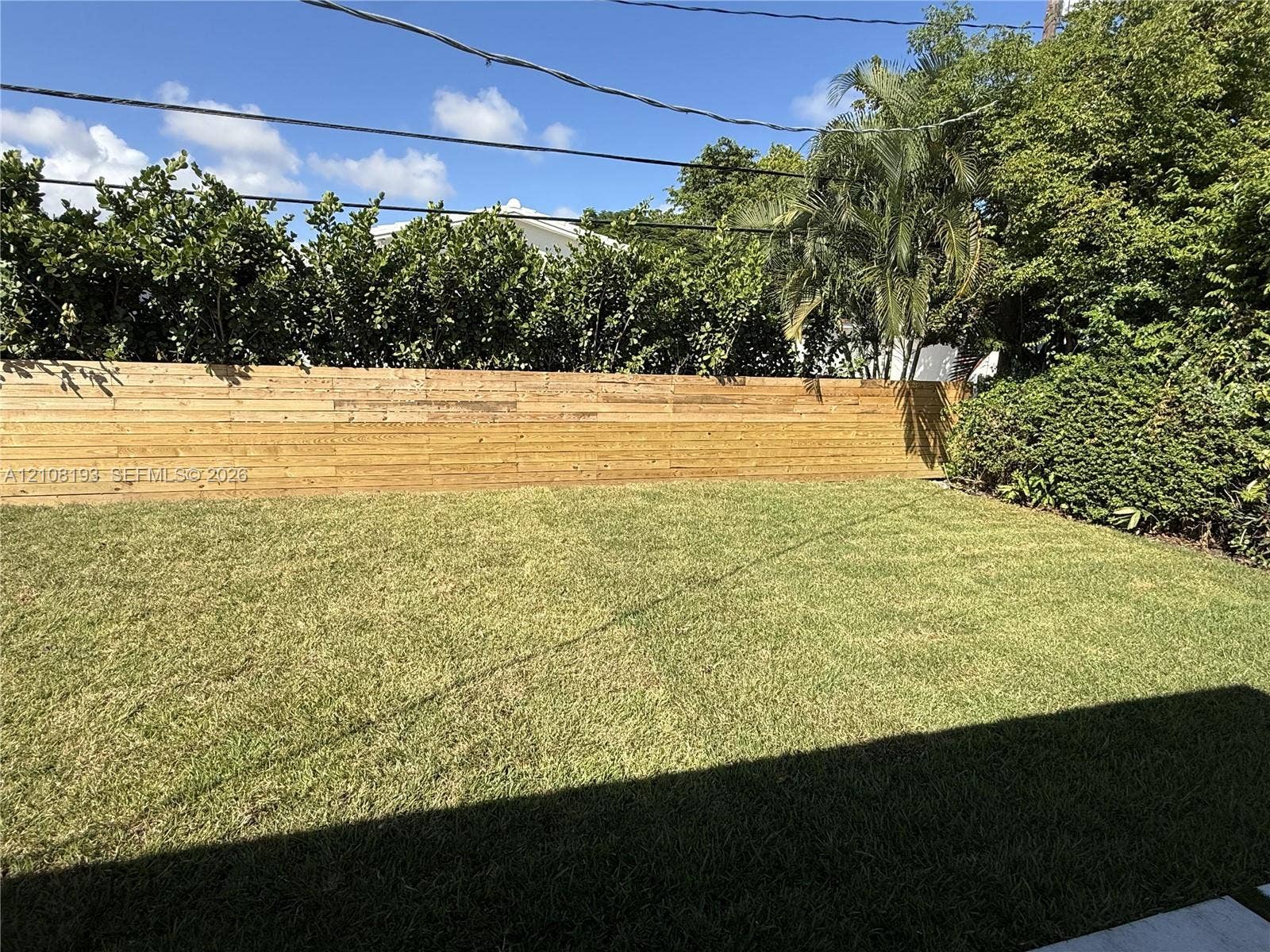 1929 SW 21st Street, #0, Miami, Miami, FL 33145 Backyard featuring a horizontal wood-slat privacy fence, manicured lawn, and mature perimeter landscaping
