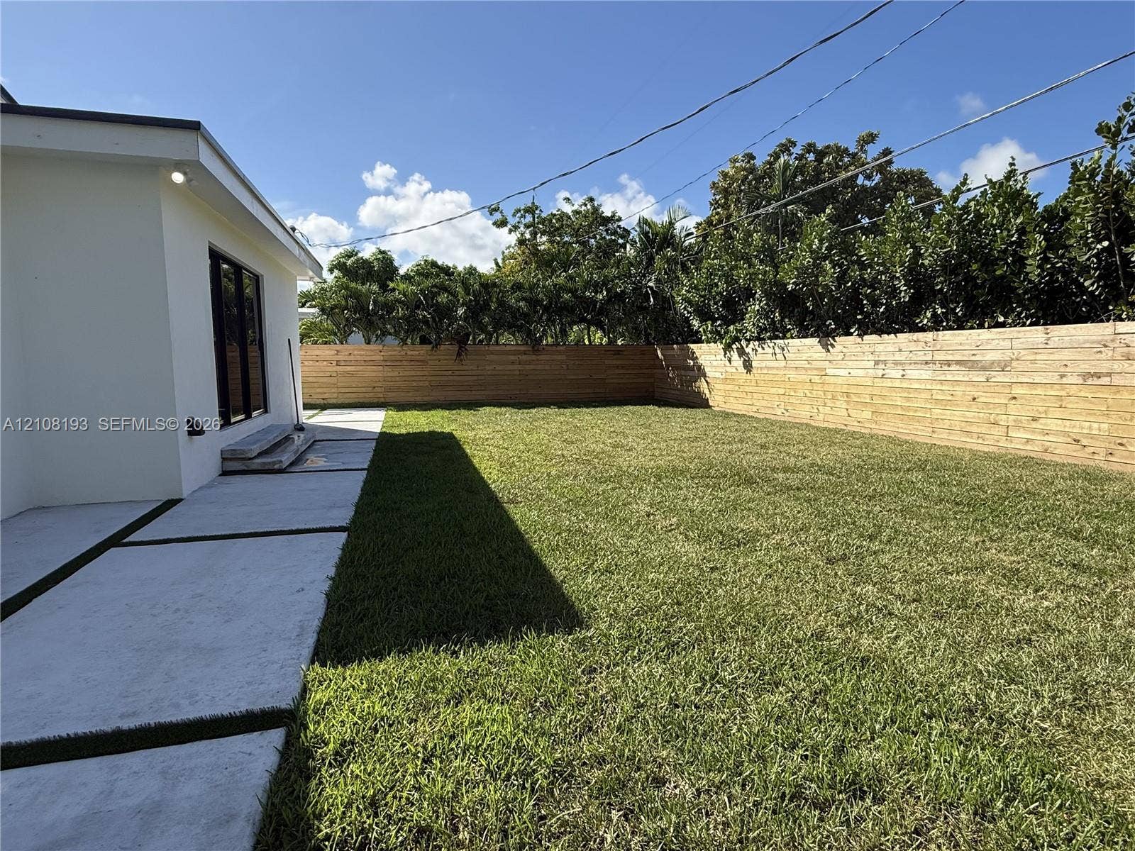 1929 SW 21st Street, #0, Miami, Miami, FL 33145 Rear exterior featuring a level grass lawn, horizontal wood perimeter fencing, and concrete paver patio with turf inlay