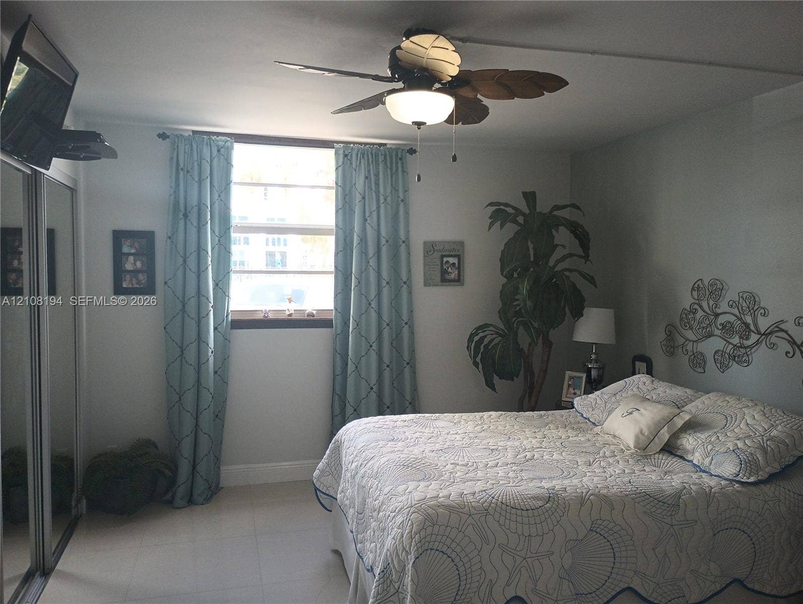 Light-filled room featuring tile flooring, sliding mirror-door closet, and a ceiling fan with integrated lighting