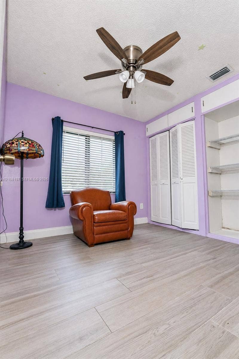 Wood-finish flooring, ceiling fan with integrated lighting, dual bifold closet doors, and open shelving