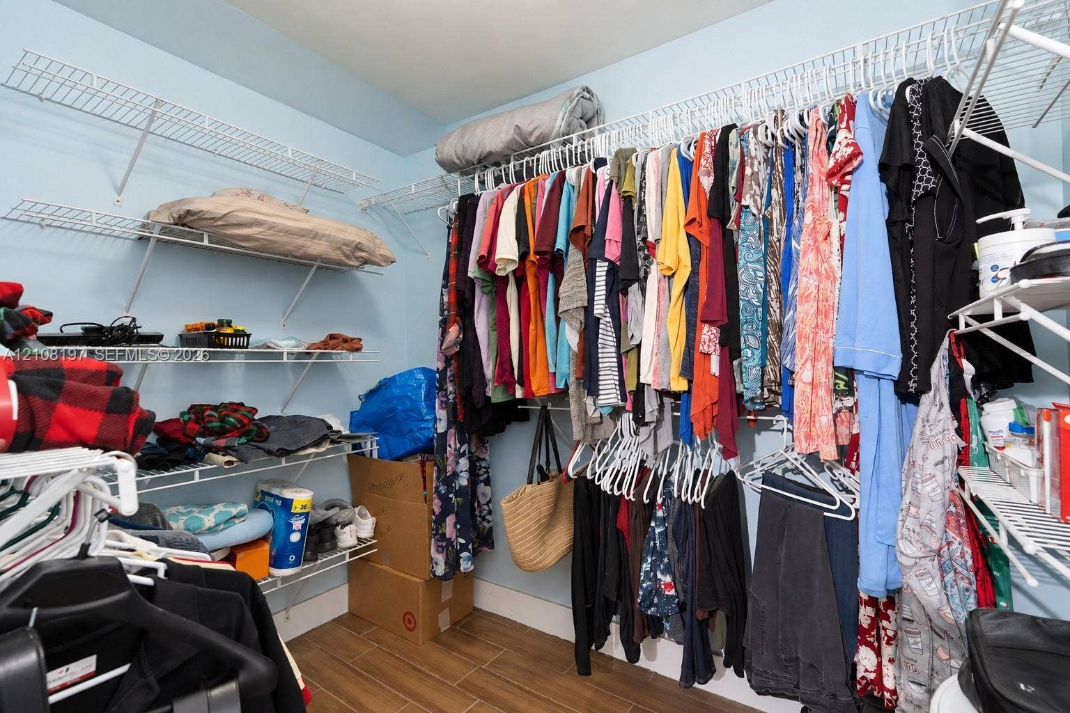 Walk-in closet featuring multi-tiered wire shelving and wood-finish flooring