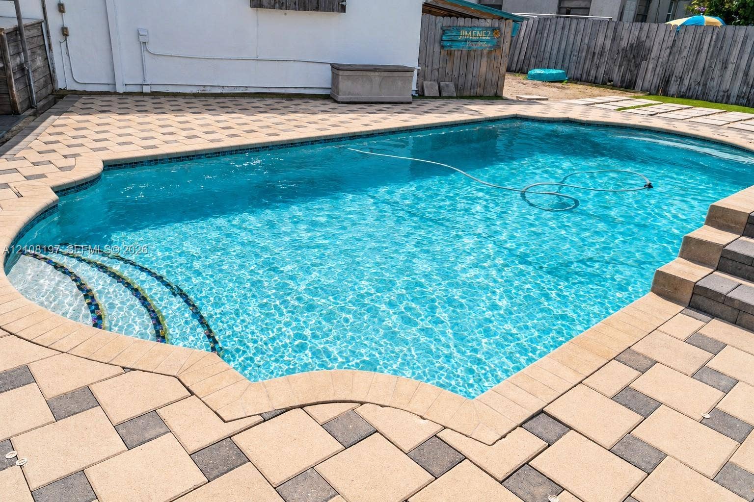In-ground swimming pool featuring a geometric stone paver deck, integrated step entry, and a multi-level block staircase