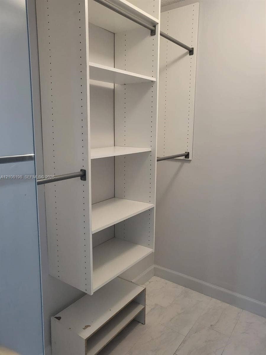 Custom white closet system featuring adjustable shelving, integrated garment rods, and lower open cubby storage