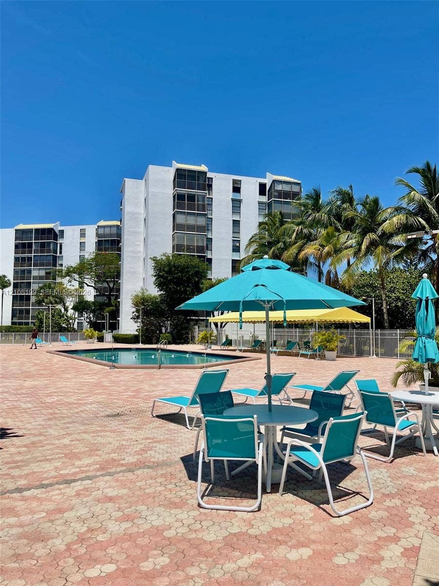 20400 W Country Club Drive, #608, Aventura, Aventura, FL 33180 Outdoor swimming pool surrounded by a paved deck featuring mature palm trees and perimeter fencing