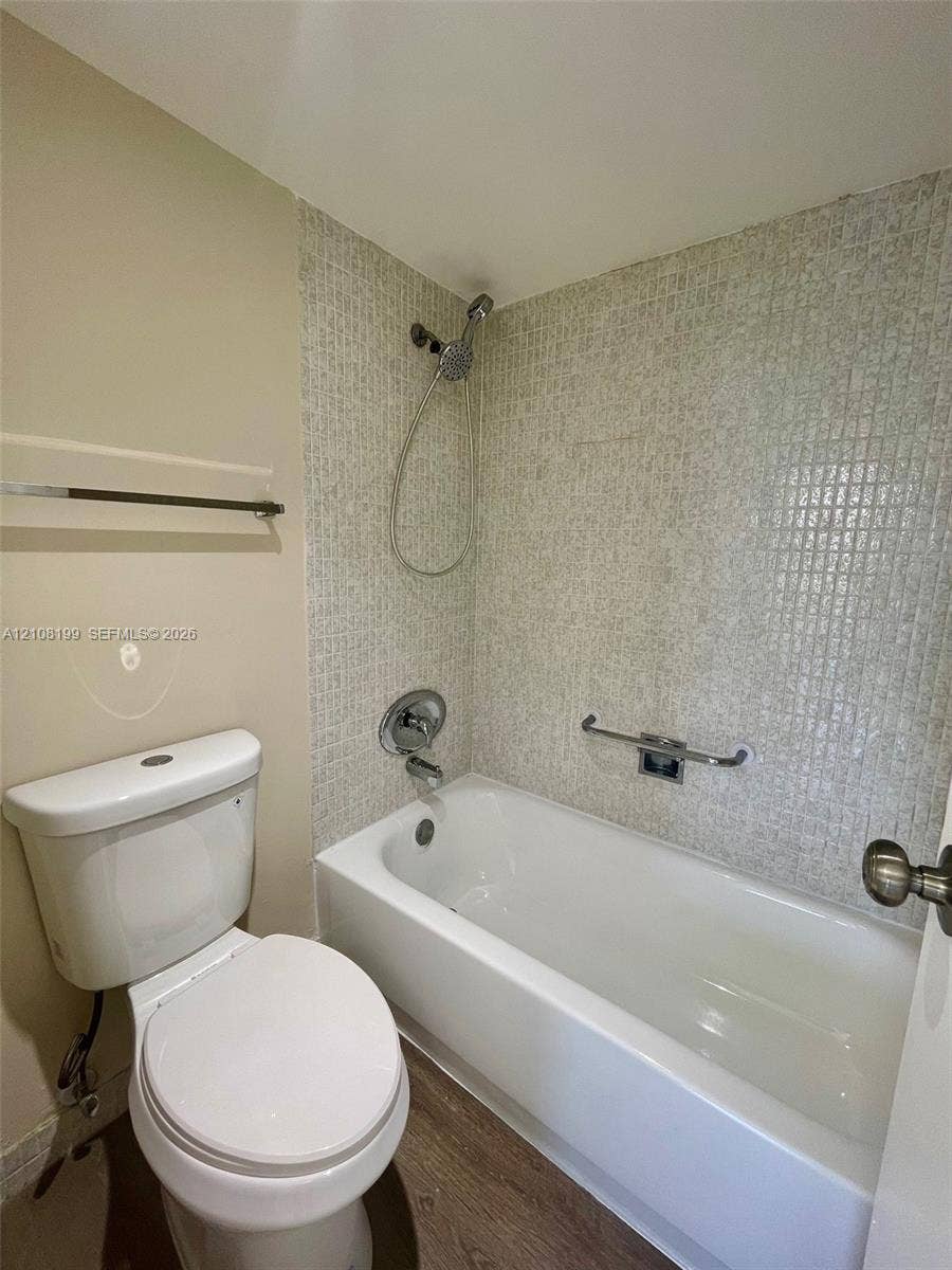 20400 W Country Club Drive, #608, Aventura, Aventura, FL 33180 Full bathtub with a handheld shower fixture, glass mosaic tile surround, wood-finish flooring, and wall-mounted metal grab bar