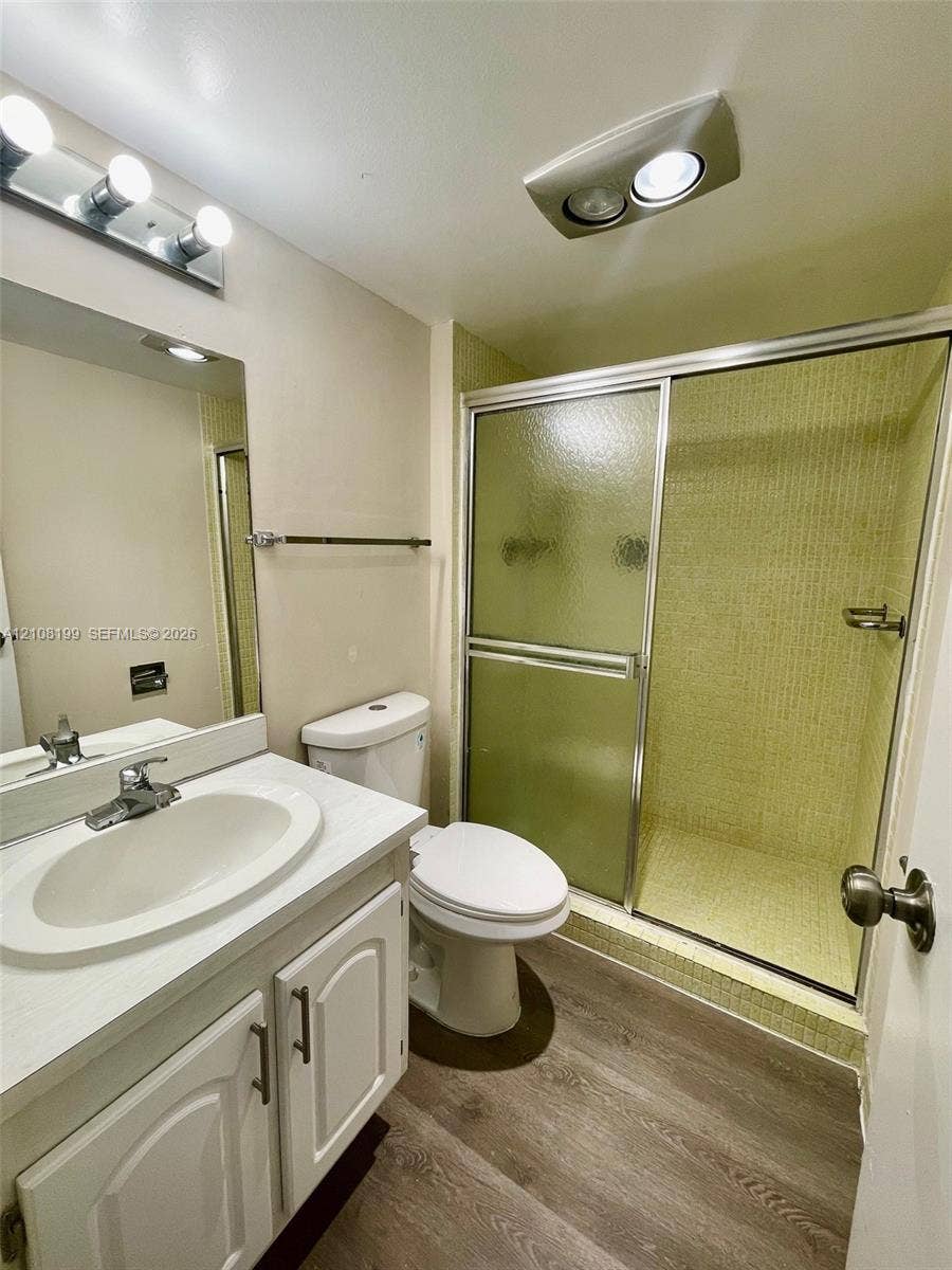 20400 W Country Club Drive, #608, Aventura, Aventura, FL 33180 Bathroom featuring a white vanity with an integrated oval sink, wood-finish flooring, and a walk-in shower with a sliding glass door and tiled surround