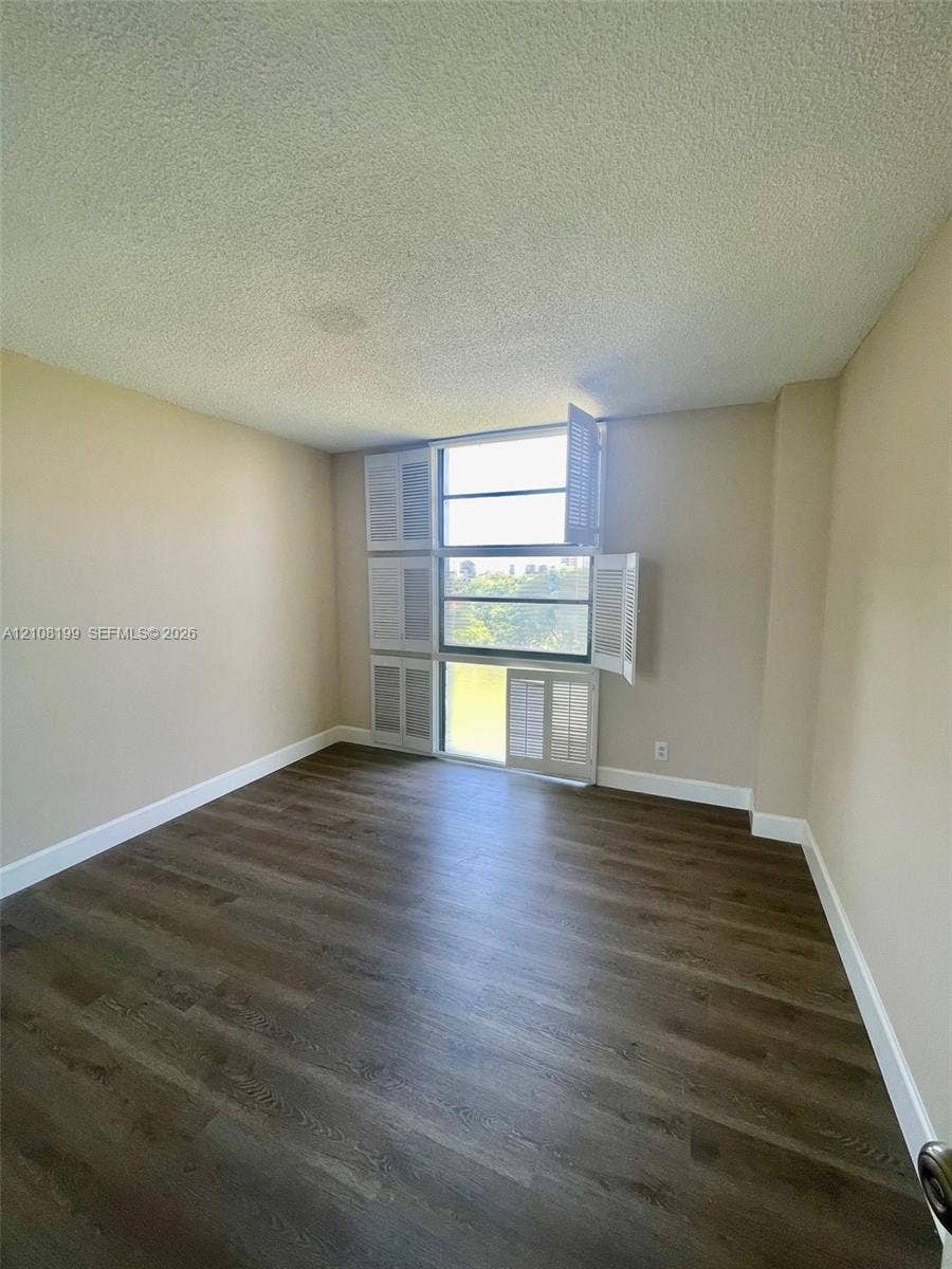 20400 W Country Club Drive, #608, Aventura, Aventura, FL 33180 Room featuring wood-finish flooring, multi-pane window with louvered shutters, and textured ceiling
