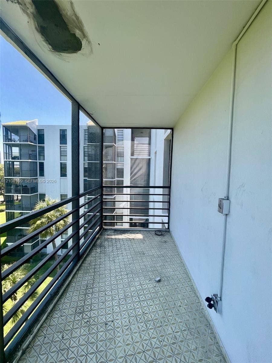 20400 W Country Club Drive, #608, Aventura, Aventura, FL 33180 Covered balcony featuring patterned tile flooring, dark metal railing, and exposed electrical fixture