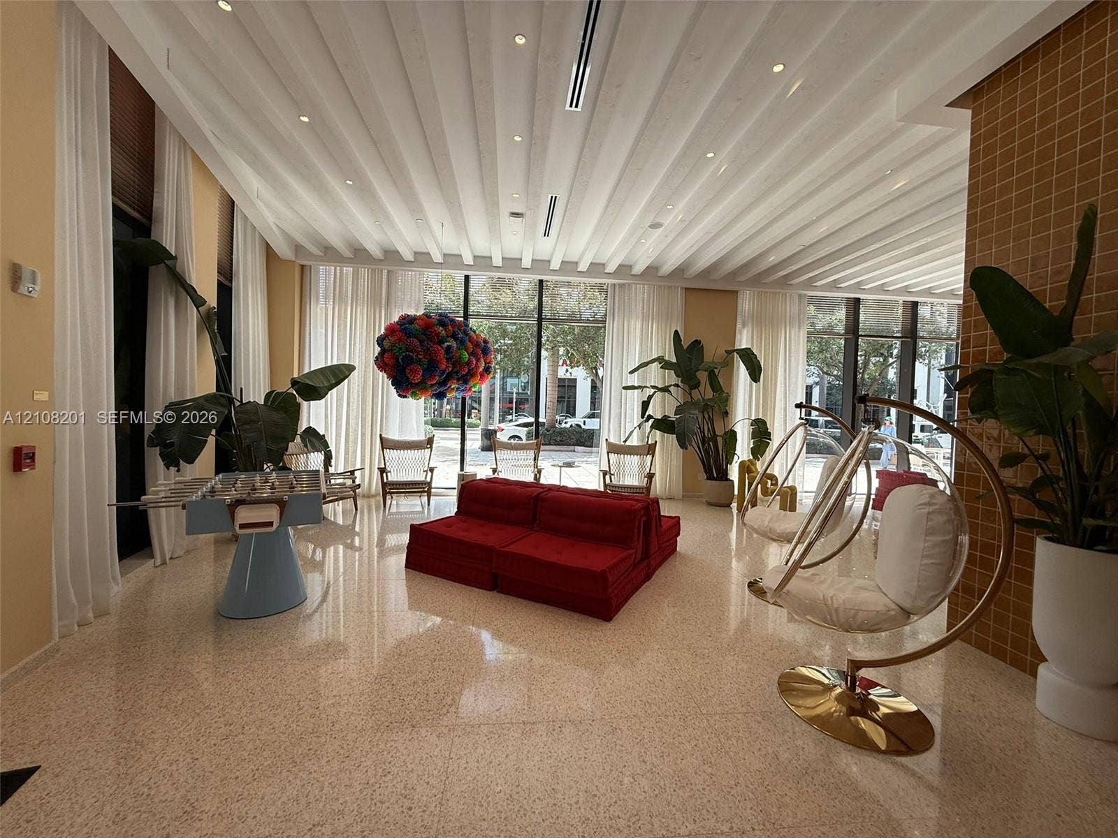 32 90 Ne 32 Street, #1115, Miami, Miami, FL 33127 Common area featuring high, vaulted ceilings with recessed lighting, full-height floor-to-ceiling windows, polished stone-finish flooring, and a decorative grid-patterned accent wall
