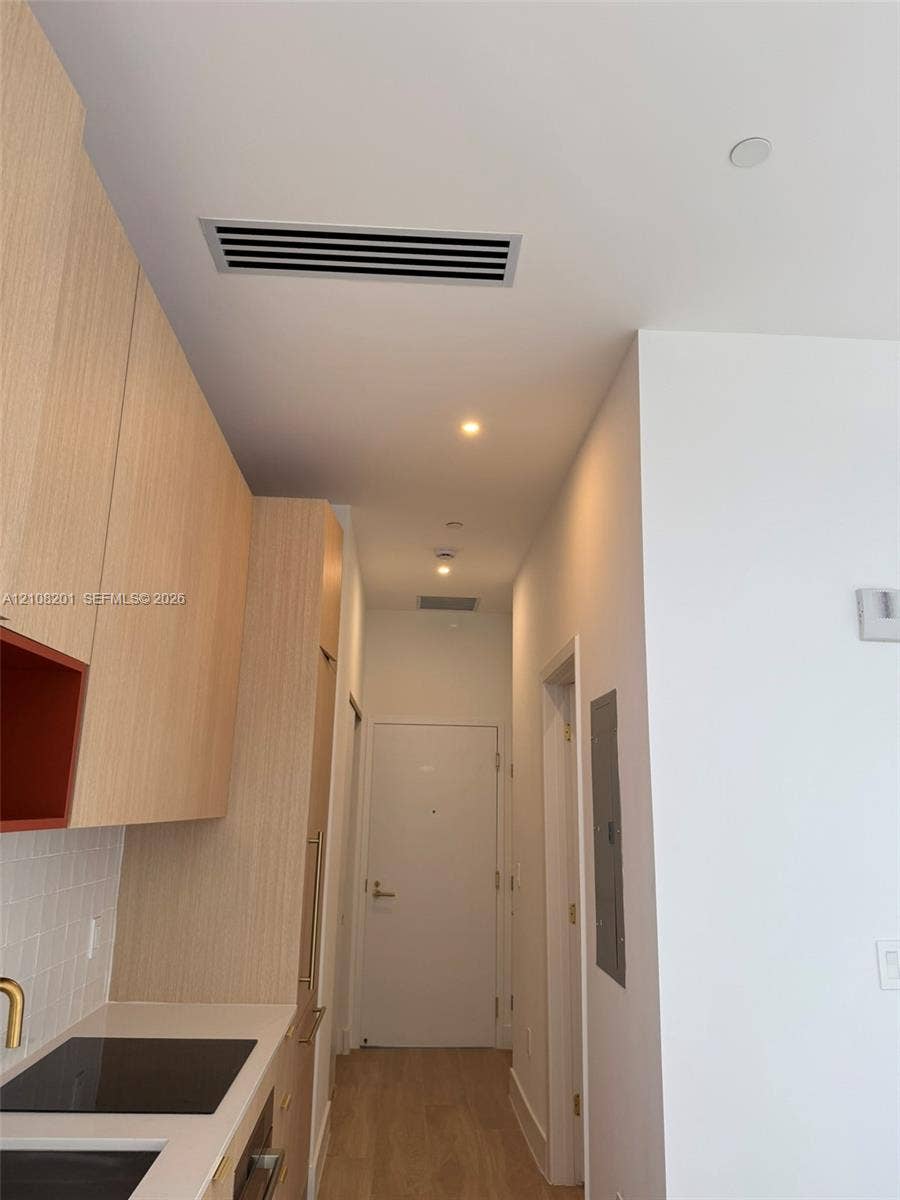 32 90 Ne 32 Street, #1115, Miami, Miami, FL 33127 Light wood-finish cabinetry, white tile backsplash, solid surface countertop, recessed ceiling lighting, and light-toned wood-finish flooring