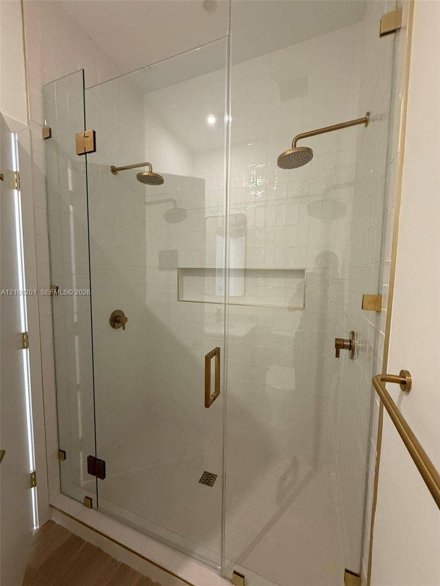 32 90 Ne 32 Street, #1115, Miami, Miami, FL 33127 Walk-in shower featuring a frameless glass enclosure, dual wall-mounted shower heads, built-in recessed storage niche, and gold-finish hardware