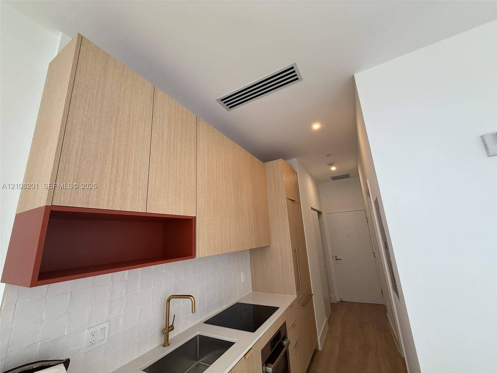 32 90 Ne 32 Street, #1115, Miami, Miami, FL 33127 Kitchen featuring wood-finish cabinetry with built-in open shelving, a white tile backsplash, a gold-tone faucet, a stainless steel sink, and a smooth cooktop
