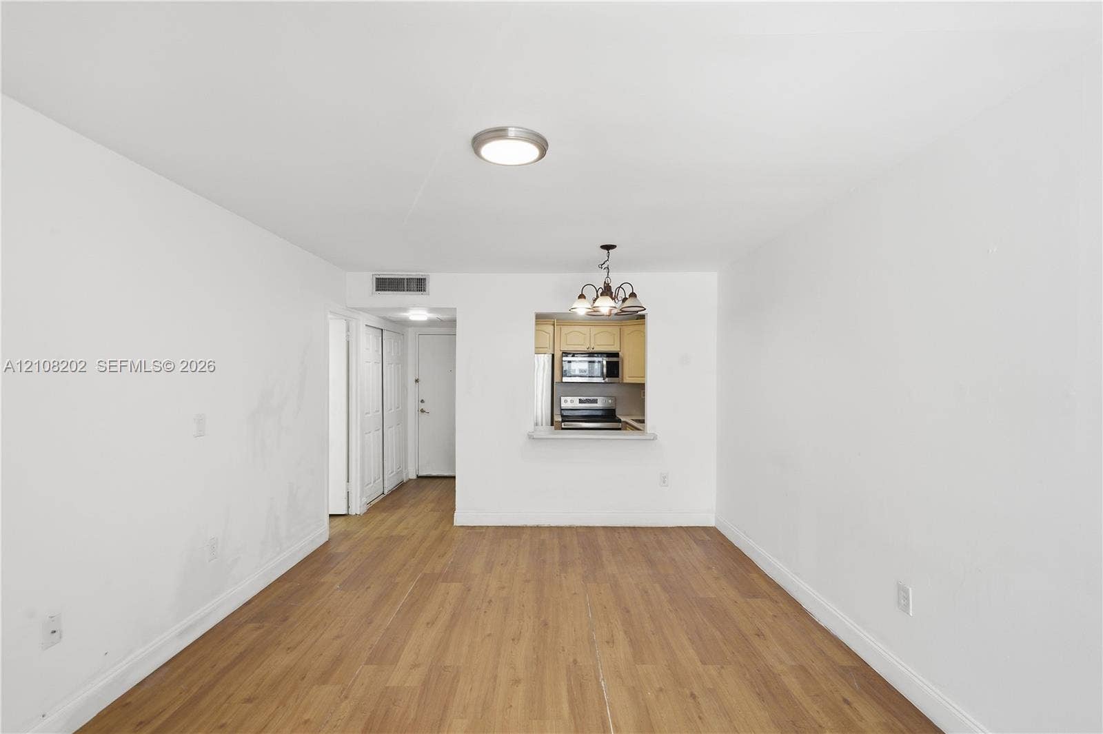 Interior space featuring wood-finish flooring, recessed ceiling lighting, a pass-through opening to the kitchen, and a kitchen featuring stainless steel appliances