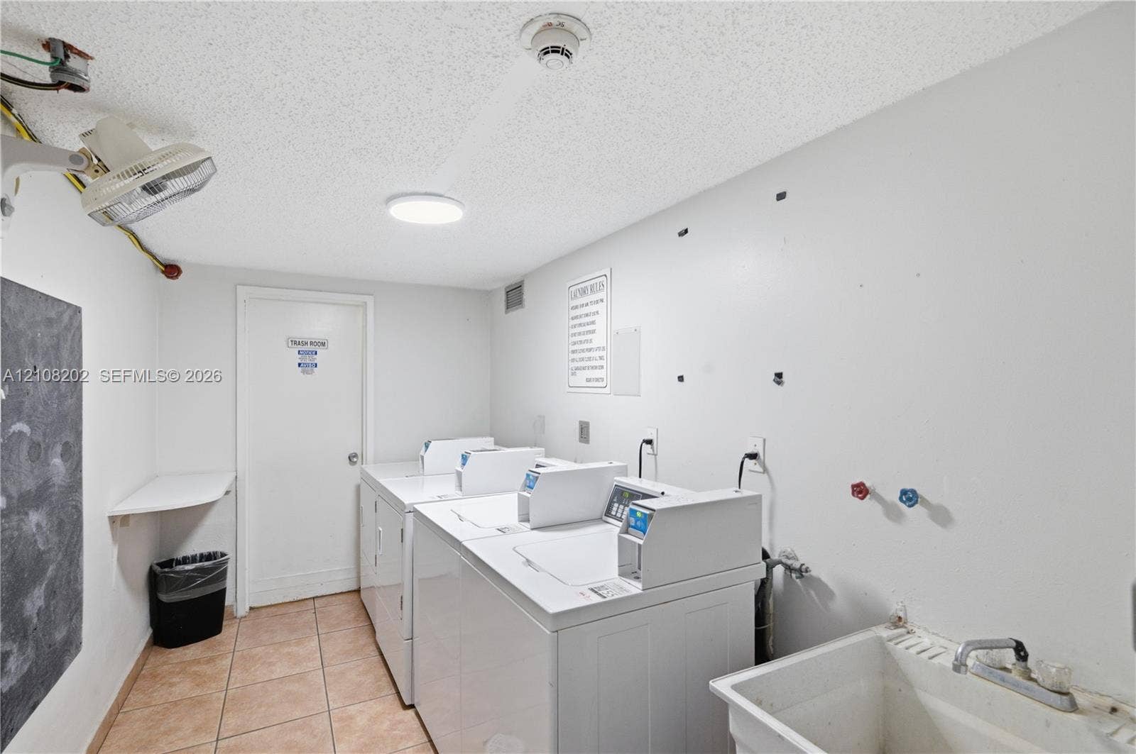 Laundry area featuring ceramic tile flooring, a wall-mounted utility sink with metal faucet, and dedicated washer and dryer hookups
