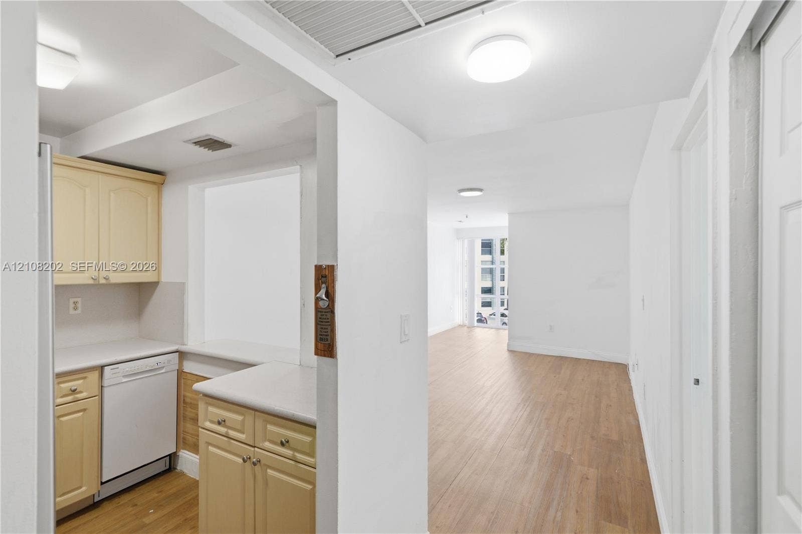 Kitchen featuring wood-finish cabinetry, solid surface countertops, a built-in dishwasher, and wood-finish flooring
