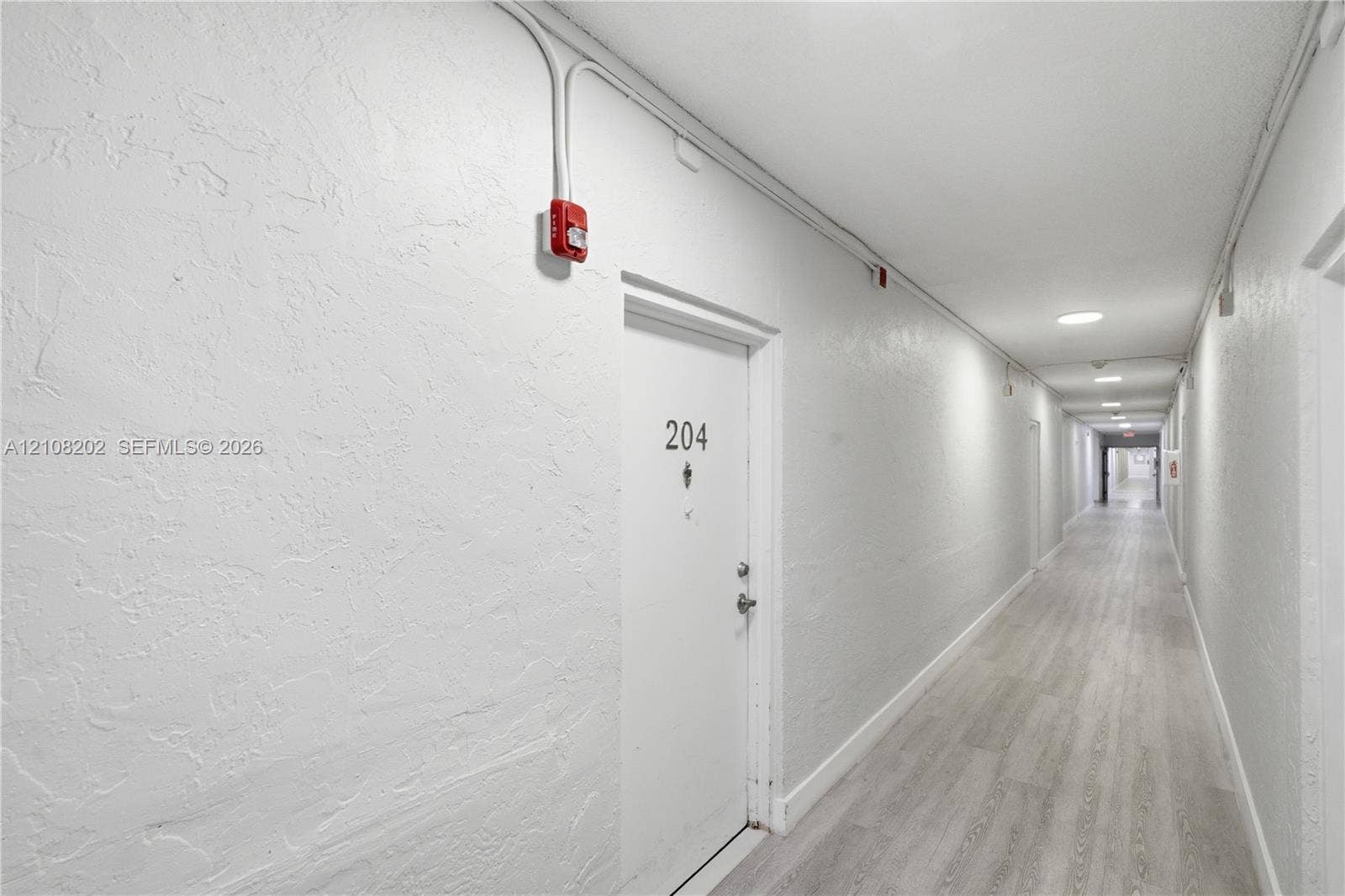 Hallway featuring light-toned wood-finish flooring and smooth white walls with recessed ceiling lighting
