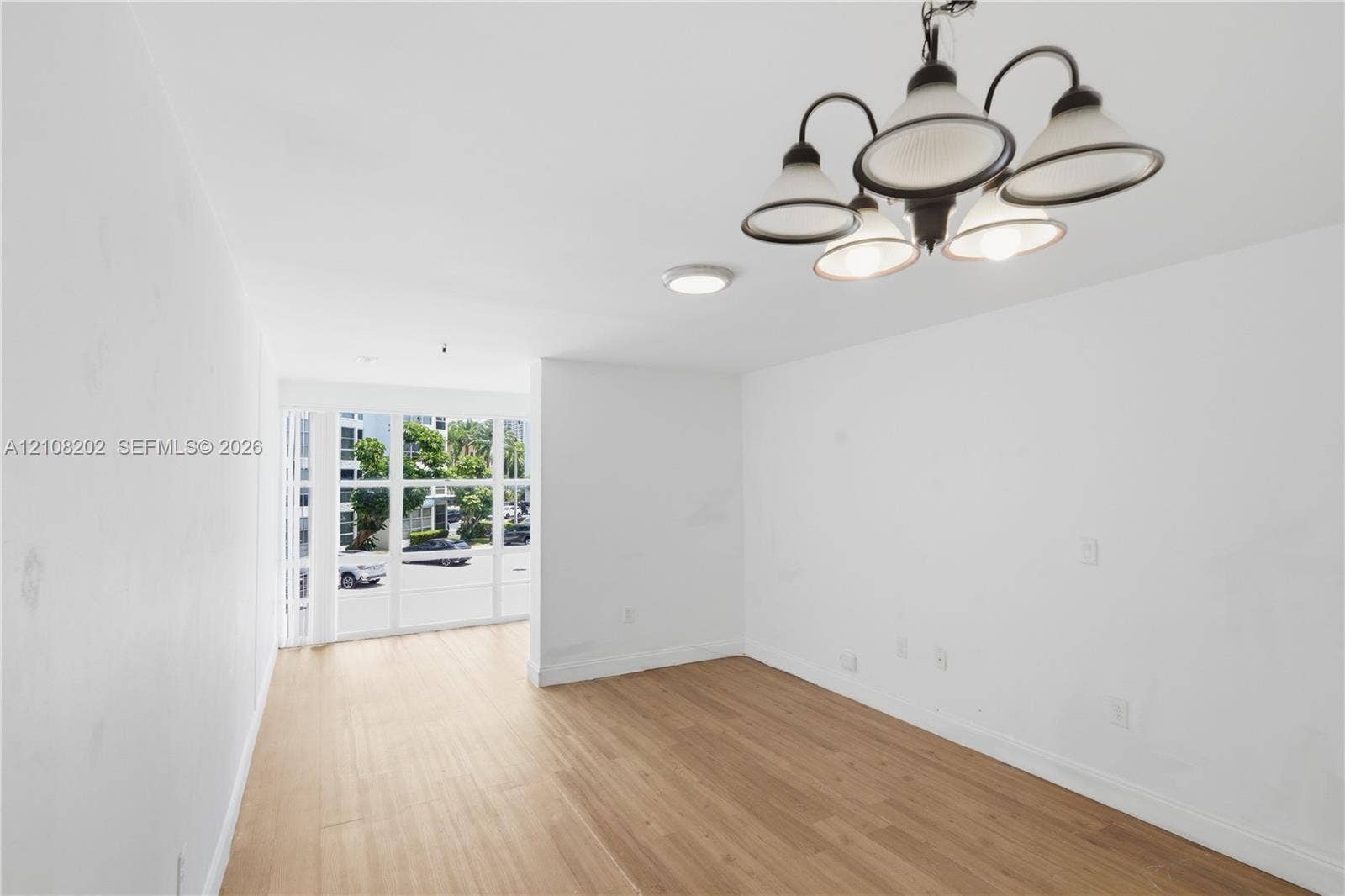 Interior space featuring wood-finish flooring, a five-arm chandelier, ceiling-mounted lighting, and large paneled windows