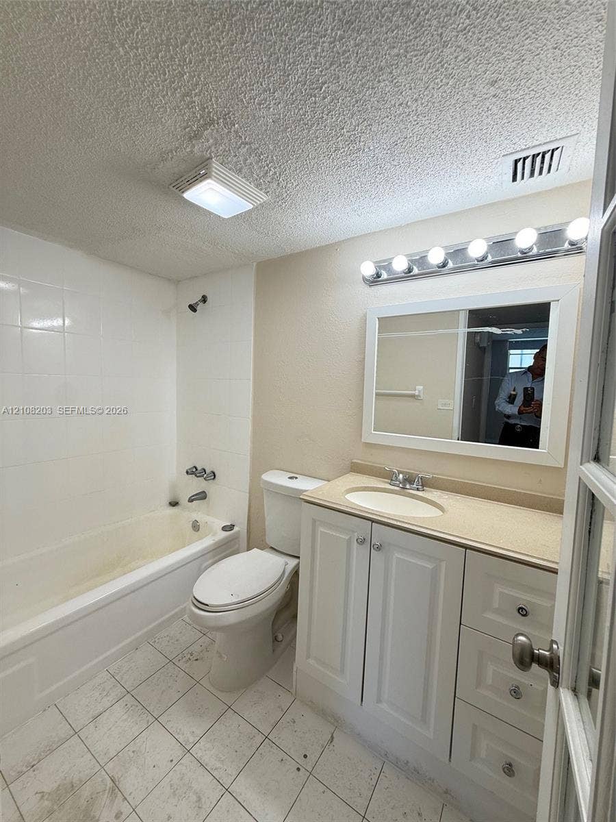 801 NW 47th Avenue, #619W, Miami, Miami, FL 33126 Bathroom featuring a white vanity cabinet with an integrated countertop and sink, a framed mirror, a multi-bulb vanity light fixture, and a tiled shower surround