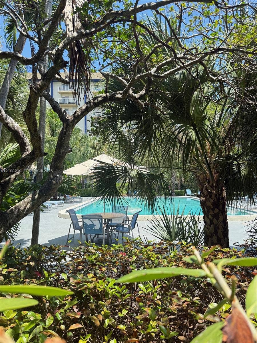801 NW 47th Avenue, #619W, Miami, Miami, FL 33126 Swimming pool with paved surround, framed by mature trees and landscaped foliage
