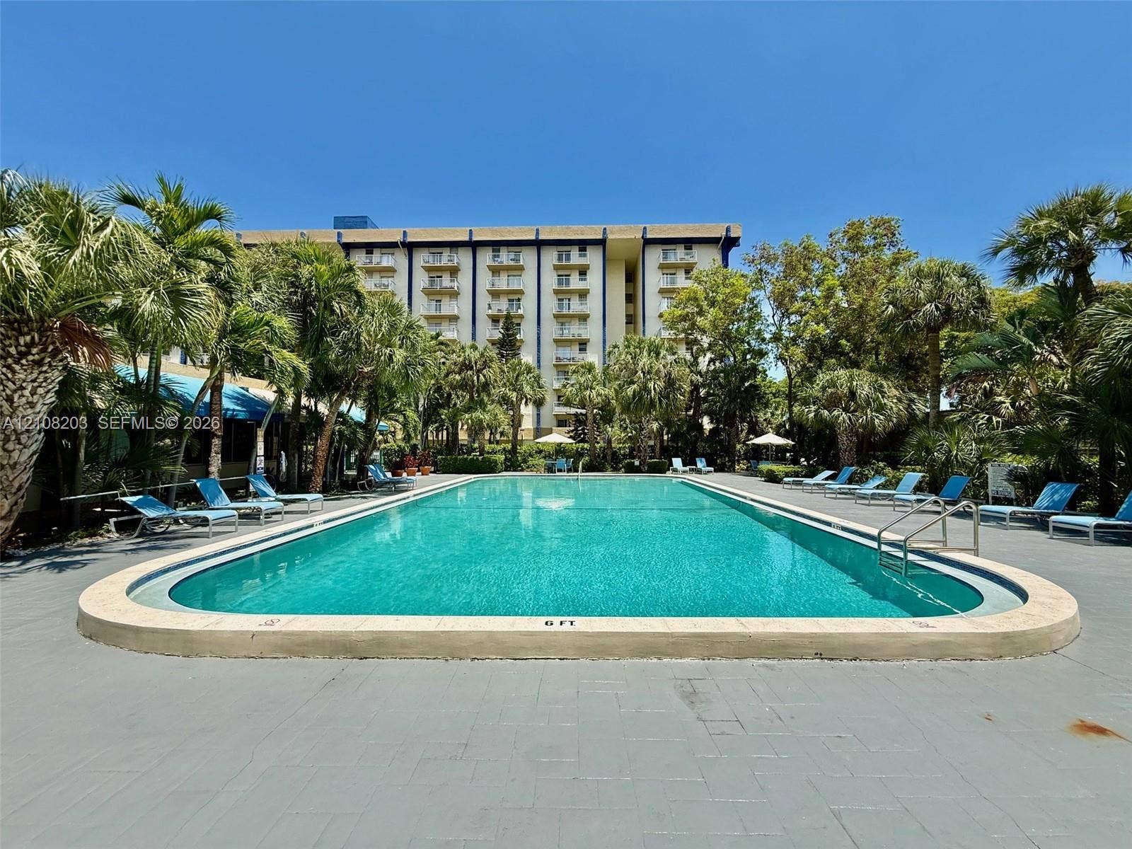801 NW 47th Avenue, #619W, Miami, Miami, FL 33126 Outdoor swimming pool featuring a concrete deck, built-in metal handrails, and surrounding palm trees